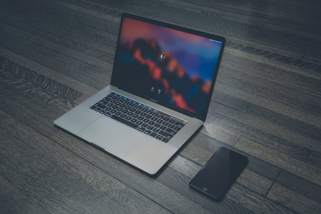 macbook-pro-and-space-gray-iphone-6-303383 A sleek laptop and smartphone placed on wooden flooring, showcasing contemporary technology.